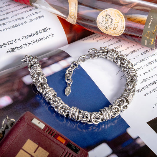 Silver bracelet on a magazine with a bottle of wine in the background